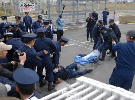沖縄平和運動センターの山城博治議長（右）の足をつかみ、引きはがすシュワブ警備員ら＝22日午前９時すぎ、名護市辺野古の米軍キャンプ・シュワブのゲート